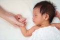 Mother holding hand of sleeping newborn baby on bed Royalty Free Stock Photo