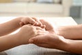 Mother holding hands with her child at table indoors, closeup. Happy family Royalty Free Stock Photo