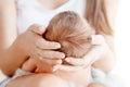 Mother holding head of her newborn baby in hands. The baby on hands at mum. Loving mother hand holding cute newborn baby child
