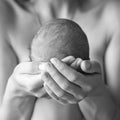 Mother holding head of her newborn son in hands. The baby on hands at mum. Loving mother hand holding cute sleeping newborn baby Royalty Free Stock Photo