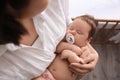 Mother holding her cute little baby with pacifier at home, above view Royalty Free Stock Photo
