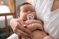 Mother holding her cute little baby with pacifier at home, closeup Royalty Free Stock Photo