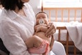 Mother holding her cute little baby with pacifier at home, closeup Royalty Free Stock Photo