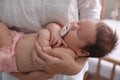 Mother holding her cute little baby with pacifier at home, closeup Royalty Free Stock Photo