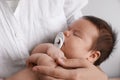 Mother holding her cute little baby with pacifier on light background, closeup Royalty Free Stock Photo