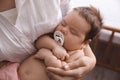 Mother holding her cute sleeping baby with pacifier at home, closeup Royalty Free Stock Photo