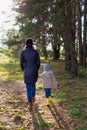 Mother holding her kid`s hand while walking together in the forest Royalty Free Stock Photo