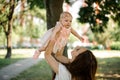 Mother holding her little daughter up in the air in the park