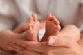 Mother holding her newborn baby, closeup view on feet. Lovely family Royalty Free Stock Photo