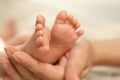 Mother holding her newborn baby, closeup view on feet. Lovely family Royalty Free Stock Photo