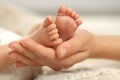 Mother holding her newborn baby, closeup view on feet. Lovely family Royalty Free Stock Photo