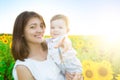 Mother holding her son in arms in sunflowers field. The boy is pointing his finger at the camera and smiling Royalty Free Stock Photo