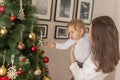 Mother holding her baby boy and decorating Christmas tree Royalty Free Stock Photo