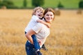 Mother holding kid boy on arms on wheat field in summer Royalty Free Stock Photo