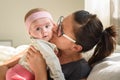 Mother holding and kissing beautiful baby girl in bright sunny room. Motherhood concept Royalty Free Stock Photo