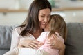 Mother holding on lap daughter embraces her enjoy tender moment