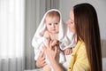 Mother holding cute little baby wrapped with towel indoors after bath Royalty Free Stock Photo