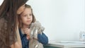 Mother holding little girl and taking her temperature with thermometer at doctor office Royalty Free Stock Photo