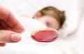 Mother holding medication in spoon foreground and sick little gi