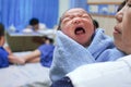 Mother holding newborn tiny baby crying.