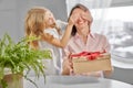 Mother holding present, daughter closing her eyers. Royalty Free Stock Photo