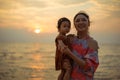 mother holding and talking toddler baby girl on sea beach at sunset Royalty Free Stock Photo