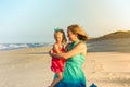 Mother holding toddler daughter on beach