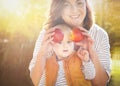 Mother holding two ripe red apples in front of face of her son. Happy child (baby boy) eating healthy food. Royalty Free Stock Photo