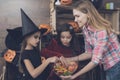 The mother is holding a vase with sweets in front of children dressed in costumes of monsters for Halloween Royalty Free Stock Photo