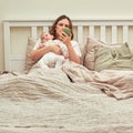 A mother holds a child in her arms and a mobile phone in the bedroom. A lonely woman with a newborn baby is lying alone in an Royalty Free Stock Photo