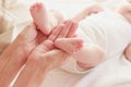 Mother holds feet of her baby in the hands, indoors, blurred background Royalty Free Stock Photo