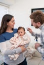 A mother holds her baby while the father is combing the baby& x27;s hair using a blue brush with soft white bristles. Royalty Free Stock Photo