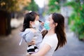 Mother holds her daughter. Mother and child wear a mask. Both looked at each other warmly.