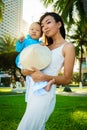 A mother holds her little daughter in traditional vietnam clothers aodai in her arms on the beach near palms