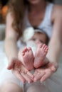 Mother holds in her palms the feet of the feet of her newborn daughter Royalty Free Stock Photo