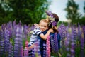 A mother holds her son in her arms in a blooming field of lilac lupine flowers