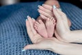 Mother holds newborn baby`s bare heels. Tiny feet in woman`s hand. Cozy morning at home. Family and home concept Royalty Free Stock Photo