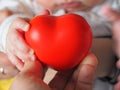 A mother holds a red heart with a small child in her hands. Concept of maternal love