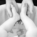 A mother holds the small legs of her newborn baby in her hands. Royalty Free Stock Photo