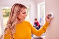 Mother At Home With Son Adjusting Smart Central Heating Thermostat Control Royalty Free Stock Photo