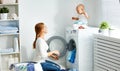 Mother housewife with baby engaged in laundry fold clothes into Royalty Free Stock Photo