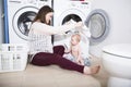 Mother a housewife with a baby engaged in laundry fold clothes into the washing machine Royalty Free Stock Photo