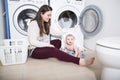 Mother a housewife with a baby engaged in laundry fold clothes into the washing machine Royalty Free Stock Photo