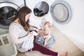 Mother a housewife with a baby engaged in laundry fold clothes into the washing machine Royalty Free Stock Photo