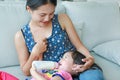 Mother hug her Cute asian child girl age about one year old and nine month drinking from a bottle Royalty Free Stock Photo