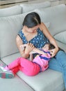 Mother hug her Cute asian child girl age about one year old and nine month drinking from a bottle on the sofa Royalty Free Stock Photo