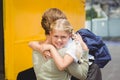 Mother hugging her daughter by school bus