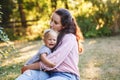 Mother hugging pacifying sad upset crying toddler girl. Family young mom and crying baby in park outdoors. Bonding relationship of