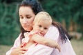 Mother hugging pacifying sad upset toddler girl. Family young mom and tired baby in park outdoor. Bonding attachment relationship