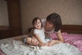 Mother hugging and playing with his daughter in bed, lifestyle,